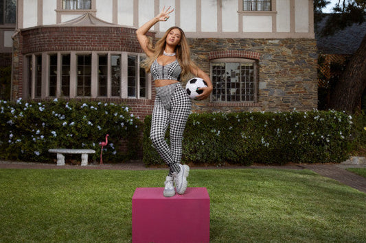 Beyoncé in a houndstooth Ivy Park crop top and leggings holding a football, from the Halls of Ivy campaign