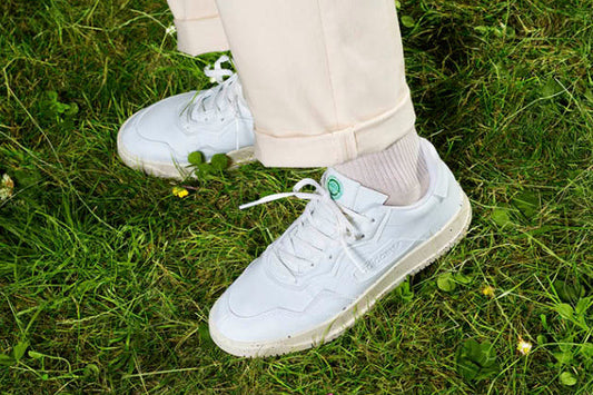 adidas Clean Classics trainers worn on grass with cream trousers