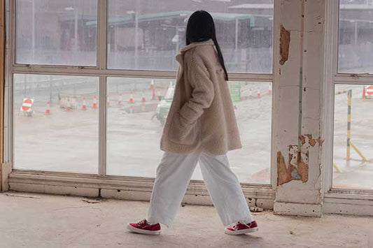 Red Vans Vault trainers worn with a cream teddy coat and white trousers, from the pam pam Praxis campaign