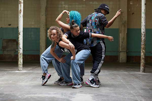 Four b-girls mid-pose in a tiled warehouse at the Old Truman Brewery, wearing adidas Falcon trainers and Originals track pants